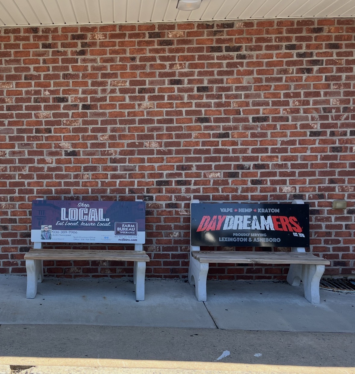 Two outdoor advertising benches with local business signs