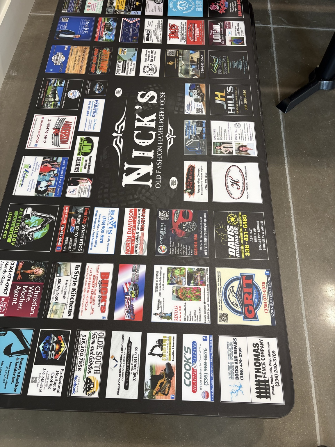 Local business advertisements surrounding the Nick’s Old Fashion Hamburger House logo on a tabletop