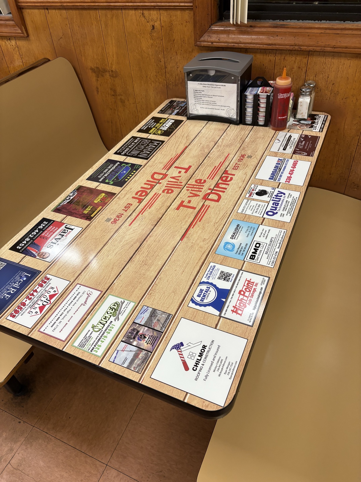 Business advertisements displayed on a wood-style tabletop at T-Ville Diner